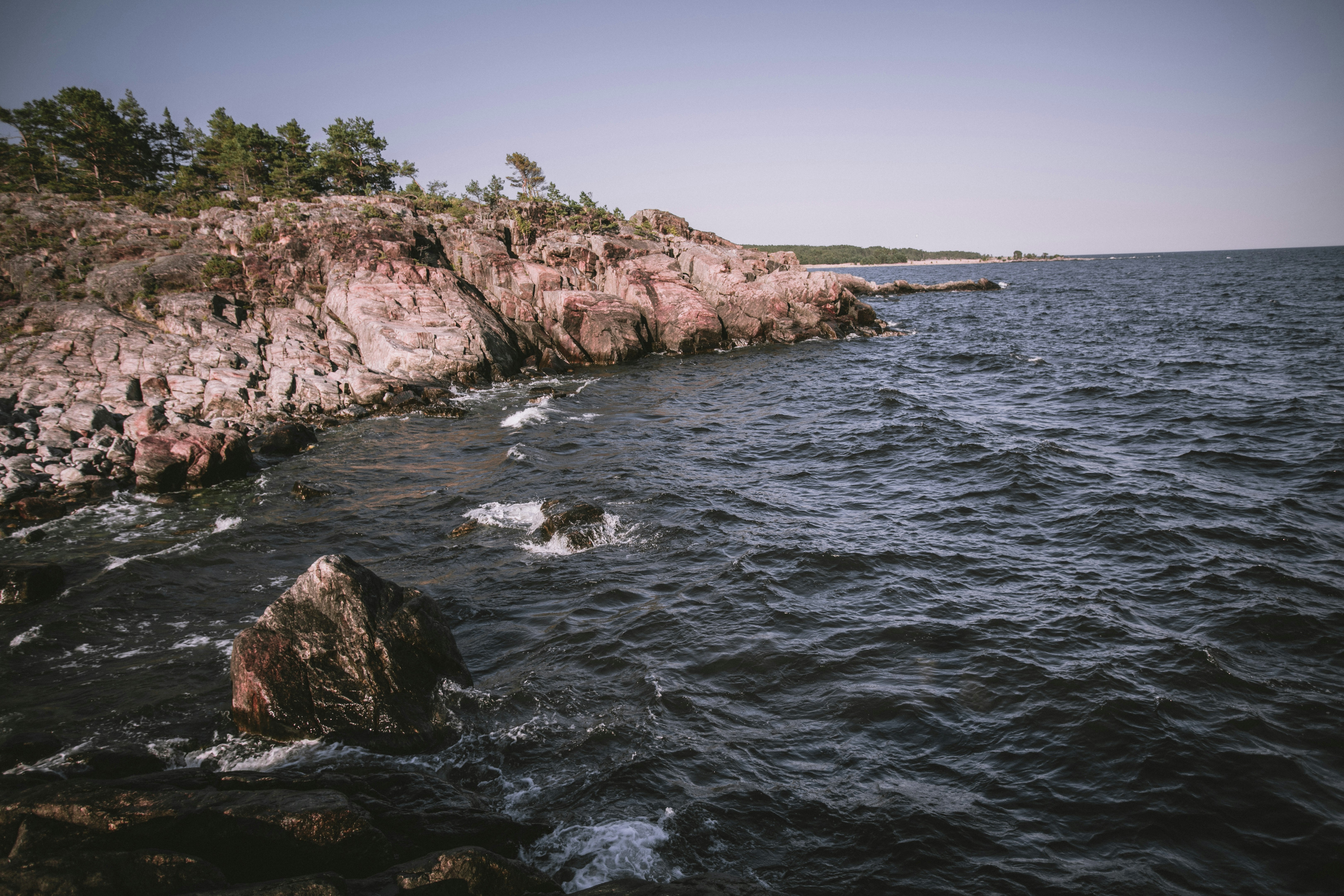 brown rocky mountain beside body of water during daytime